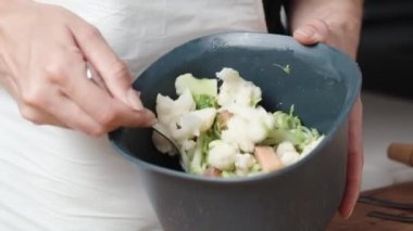 Kadın renkli lahana ve somon etini kasede karıştırıyor..