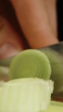 Dikey video. Pırasayı dilimleyip parçaları kameraya doğru topluyorum. Dolly kaydırıcı aşırı yakın çekim.