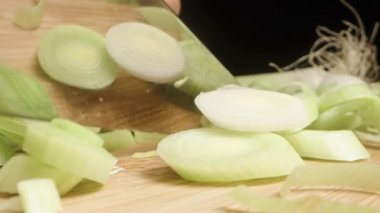 Tahta kesme tahtasındaki yeşil pırasayı siyah arka planda kesiyorum, makro çekim..