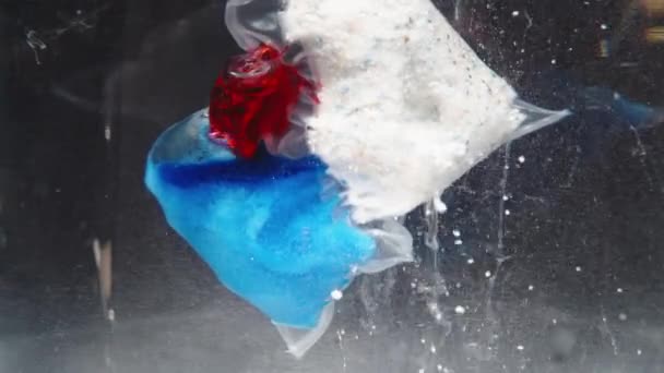 세척기가 수중에서 용해되는 패킷의 클로즈업 파란색 분말은 물에서 천천히 방출되고 — 비디오
