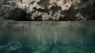 Suyun kenarındaki kamera aynı anda su altında ve suyun üstünde iki farklı perspektif yakalayarak kayalık oluşumları gösteriyor..