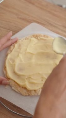 Dikey video. Napolyon keki hazırlamak için puf böreğine beyaz krema döken bir kadının en iyi görüntüsü..