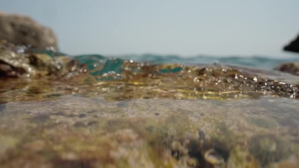 摄像机躺在海边的岩石上 海浪慢吞吞地掠过岩石 拍到了近景 — 图库视频影像