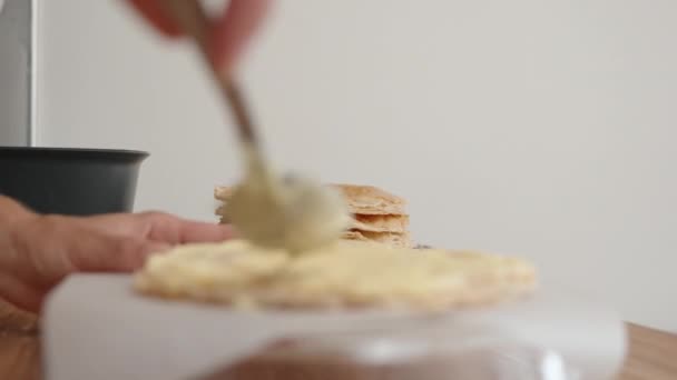 一个女人正在用勺子把奶油均匀地铺在糕点上做拿破仑蛋糕 — 图库视频影像