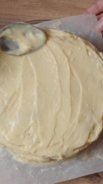 Dikey video. Yukarıdan bakıldığında, pastacı kremayı Napolyon pastasının üstüne sererken görülüyor. Yavaş morion