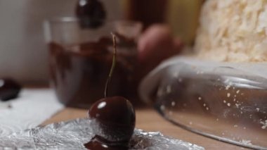 Çikolatayla kaplanmış ve kurutmak için folyonun üzerine konmuş bir kirazın yakın plan çekimi..