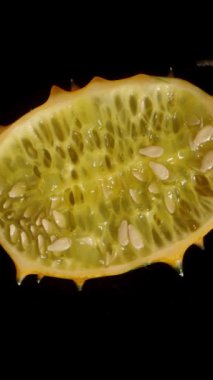 Dikey video. Yarım kiwano. İçerideki et ve tohumları gösteriyor. Siyah arka planda rotasyon. Tek atış..