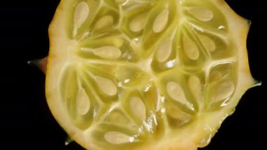 Kiwano 'nun yarısı dönüyor, içindeki et ve tohumları gösteriyor. Makro görünüm.