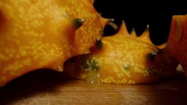 Masada dilimlenmiş Kiwano salatalıkları, siyah arka planda keskin parçalar. Dolly kaydırıcı aşırı yakın çekim.