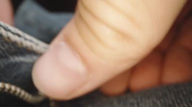 Kamera geriye doğru hareket ederken, mavi kot pantolondaki metal fermuarı kapatıyorum. Makro yakın plan.