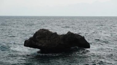 Deniz manzarası ve sudan çıkan küçük bir kaya, ağır çekimde..