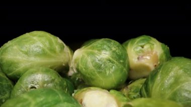 Kamera ilerlerken ve bir kadının eli onları birer birer çekerken, pişmiş Brüksel lahanalarından oluşan dağlar. Dolly kaydırıcı aşırı yakın çekim.