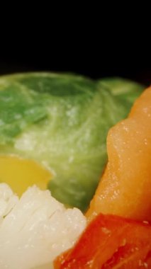 Dikey video. Brokoli, lahana, havuç ve biber gibi çiğ sebzelerin karışımı. Sağlıklı ve besleyici sebze kombinasyonu. Dolly kaydırıcı aşırı yakın çekim.