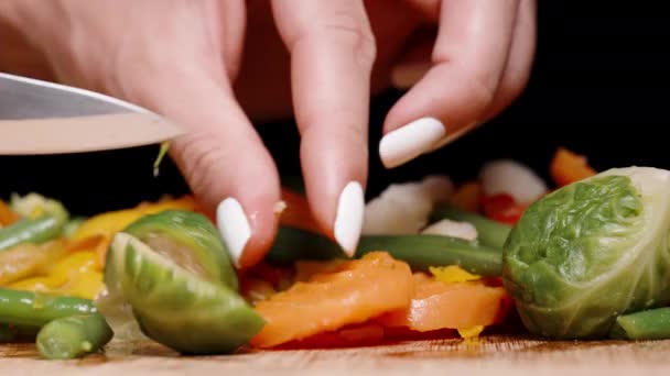 黒い背景に生野菜を切った女性のクローズアップ ブリュッセルはニンジンとコショウの間で芽を出し豆 — ストック動画