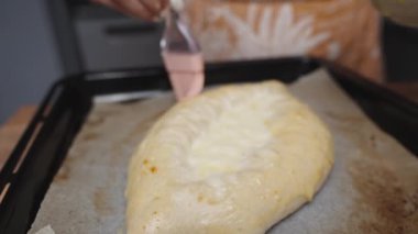 Bir kadın, Adjaran Khachapuri 'ye çırpılmış yumurta uygular. Yavaş çekim.