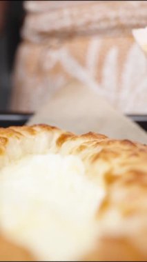 Dikey video. Kadın, Ajarian Khachapuri 'nin içindeki erimiş peynirin üzerine yavaş çekimde çiğ yumurta döküyor..