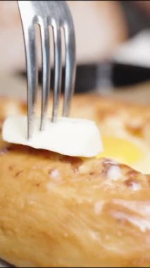 Dikey video. Sıcak Ajarian Khachapuri 'nin üzerine biraz erimiş tereyağı sürdüm..