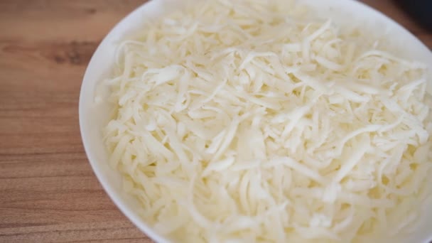 Ein Weißer Teller Mit Geriebenem Käse Auf Einem Holztisch Draufsicht — Stockvideo