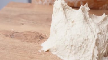 Ahşap masaya yoğururken hamurlar kadının eline yapışır..