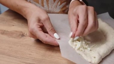 Kadın Adjarian Khachapuri yapıyor, rendelenmiş peyniri hamura sarıyor..