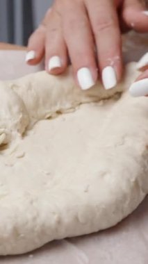 Dikey video. Kadın Khachapuri 'yi hazırlıyor, hamuru tekne şeklinde şekillendiriyor..
