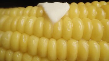 Bir parça tereyağı kaynamış mısırın üzerinde eriyor ve damlıyor. Kaydırma hareketiyle makro çekim.