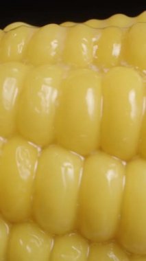 Dikey video. Erimiş tereyağını sıcak mısırın üzerine sürdüm ve damlalar çekirdeklere aktı. Kaydırma hareketiyle makro çekim.