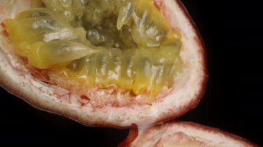 Siyah arka planda iki parça tutku meyvesi, damlacıklar birbiri ardına damlıyor. Kaydırma hareketi.