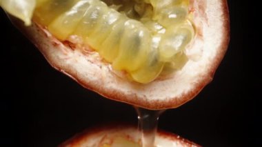 Dilimlenmiş tutku meyvesinin iki yarısının Macro kaydırak iğnesi, su damlacıkları düşüyor. Kamera aşağı doğru hareket ediyor..