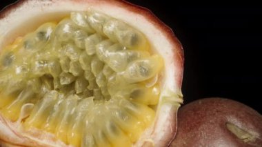 Bir tutku meyvesinin içine yakın çekim tohumları, siyah bir arkaplanda kayar..