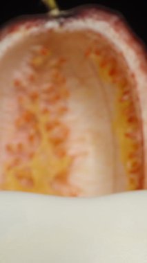 Dikey video. Temizlenmiş tutku meyvesi ve meyve suyu beyaz bir tabakta toplanır. Dolly kaydırıcı aşırı yakın çekim.