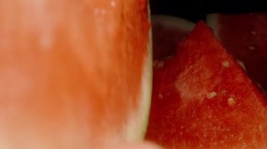 Bir adam karpuz dilimini kemirirken kamera yavaşça geriye doğru hareket ediyor..