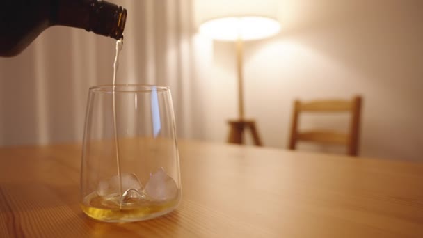 Whisky Giet Van Een Zwarte Fles Een Glas Met Ijs — Stockvideo