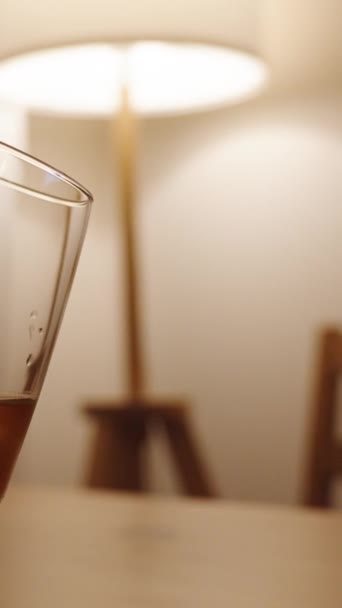 垂直录像 男人拿着一杯威士忌 女人则把杯子靠得更近 并把杯子和他的杯子连在一起 天已黑了 他们身后一盏灯发出温暖的光 — 图库视频影像
