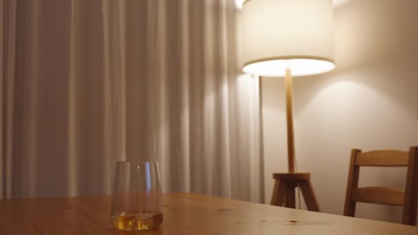 一只女手从木桌上拿起一杯威士忌 点着昏暗的灯光 — 图库视频影像