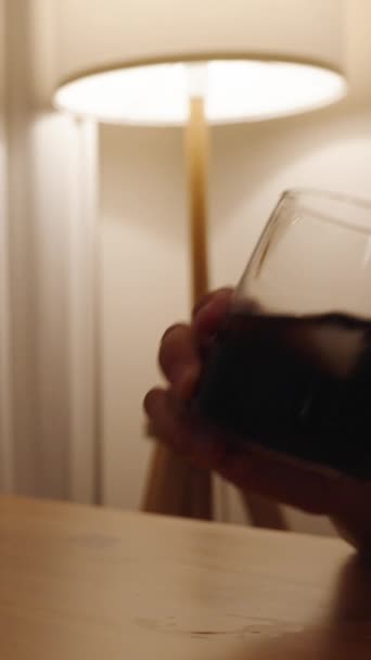 垂直录像 桌上放着两杯威士忌和可乐 桌子后面放着白色的窗帘和一盏落地灯 那个男人一个人喝酒 — 图库视频影像