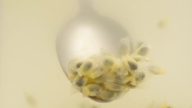 Yakın çekimde, tutku tohumlarını bardaktan bir kaşık kullanarak çıkarmaya çalışıyorum..