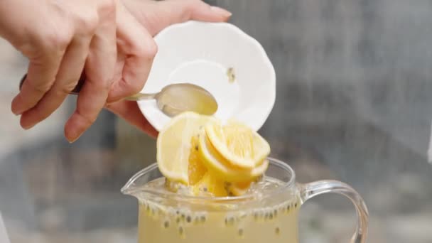 慢动作时 女人从碗里把柠檬和橙子片倒入盛有激情果汁和种子的水壶里 — 图库视频影像