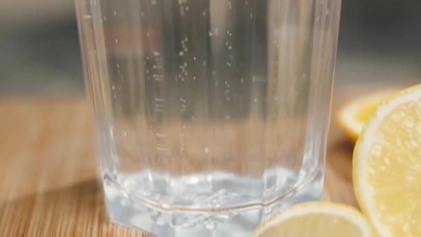 玻璃杯里盛满了苏打水 旁边的木制桌子上放着柠檬片 — 图库视频影像