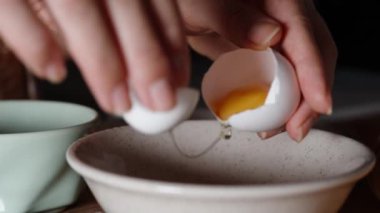 Bir kadın yumurtanın beyazını kabuğun içindeki sarıdan ayırır. Yavaş çekimde, yakın çekimde..