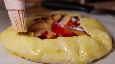 Şeftalili turtanın kenarları fırçayla fırçalanarak altın bir kabuk oluşturulur..