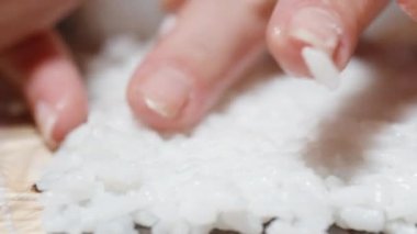 Kadın, yakın plan çekimde Norveç çarşaflarındaki pirinç tabakasını eşitliyor..