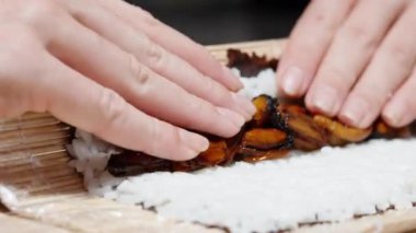 Kadın suşiyi pirinç ve midyeyle yuvarlıyor..