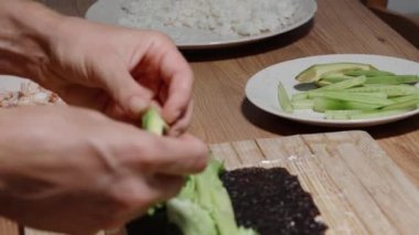 Avokado, suşi hazırlığı sırasında salata yaprakları, nori ve pirinçten oluşan bir yatağa yerleştirilir..