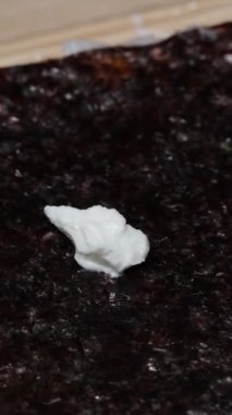 Dikey video. Krem peynir kurutulmuş yosun çarşaflarına yayılır..
