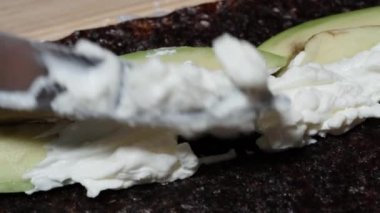 Krem peynir, avokado, nori yosun çarşafları ve suşi rulolarının üzerine yayılır..