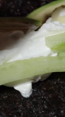 Dikey video. Krem peynirin üzerine salatalık dilimleri konur, suşi ruloları için dolgu olarak servis edilir..