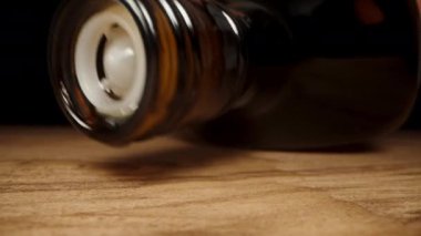 Boş siyah viski şişesini masaya koyuyorum, ve son damlalar da ahşap yüzeye damlıyor, makro sürgülü..