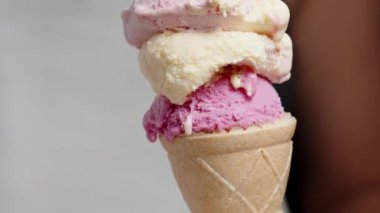 Pembe tonlarda dondurma kepçesi olan bir waffle külahı. Kaptaki özel kaşıkla kepçeleyen bir kadın..