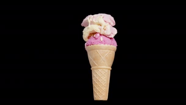 隔離された黒い背景で回転するピンク色のトーンで多色のアイスクリームのスクープが付いているワッフルコーン — ストック動画